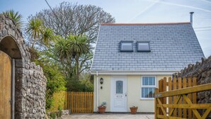 Une maison avec un mur en pierre, un portail en bois et une allée pavée.