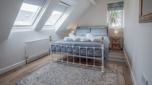 Une chambre à coucher avec un lit, une table de chevet, une fenêtre donnant sur un beau paysage et un radiateur.