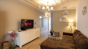 Un soggiorno moderno con una TV a schermo piatto, un mobile TV bianco, un divano marrone e un tavolino con una lampada.