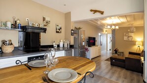 Una cucina moderna con zona pranzo, dotata di fornello, frigorifero e televisore a schermo piatto.
