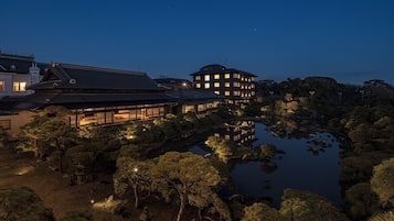 A traditional Japanese building with a pond in the foreground, surrounded by trees.