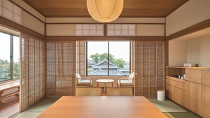 Une pièce de style japonais traditionnel, avec un sol recouvert de tatamis, une table en bois et des chaises.