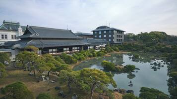 A traditional Japanese building complex with multiple structures, a pond, and surrounding trees.