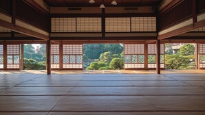 Une pièce de style japonais traditionnel, avec un sol recouvert de tatamis, des portes coulissantes en papier de riz (shoji) et une vue sur un jardin.