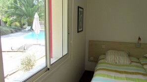 Quarto com cama, janela e vista para a piscina e área de pátio.