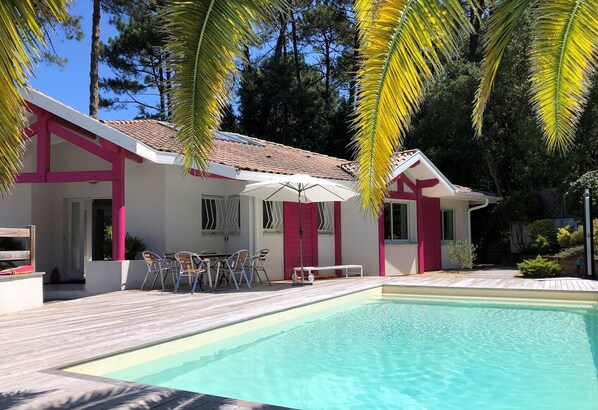 Uma casa moderna com piscina, móveis de exterior e esquema de cores vermelho e branco.