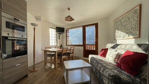 Una cucina moderna con forno e zona pranzo con tavolo e sedie. C'è un divano con cuscini decorati e un cuscino rosso.