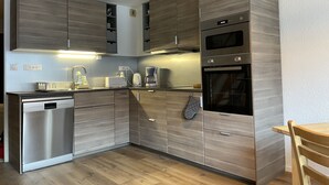 Una cucina moderna con mobili in legno, lavastoviglie integrata, macchina del caffè e forno.