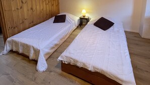 Una stanza con due letti, un lucernario, pareti in legno e un piccolo tavolo con una lampada.