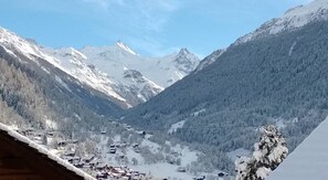 Un paysage de montagne avec des sommets enneigés et une vallée parsemée de bâtiments.
