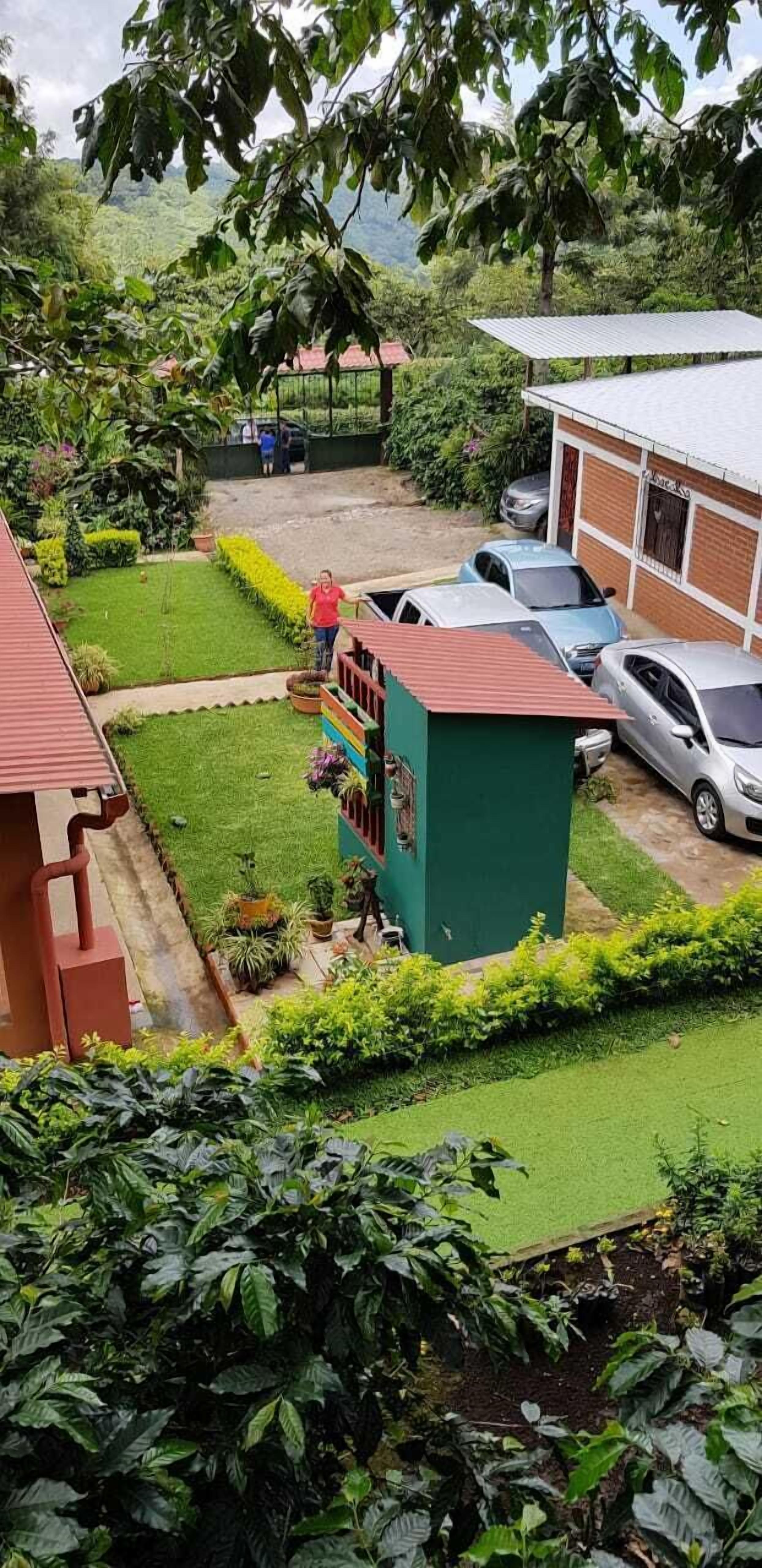 Zona residenziale con una casa verde, un piccolo giardino e auto parcheggiate.