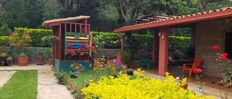 A garden with a small structure, a patio area, and a brick building.