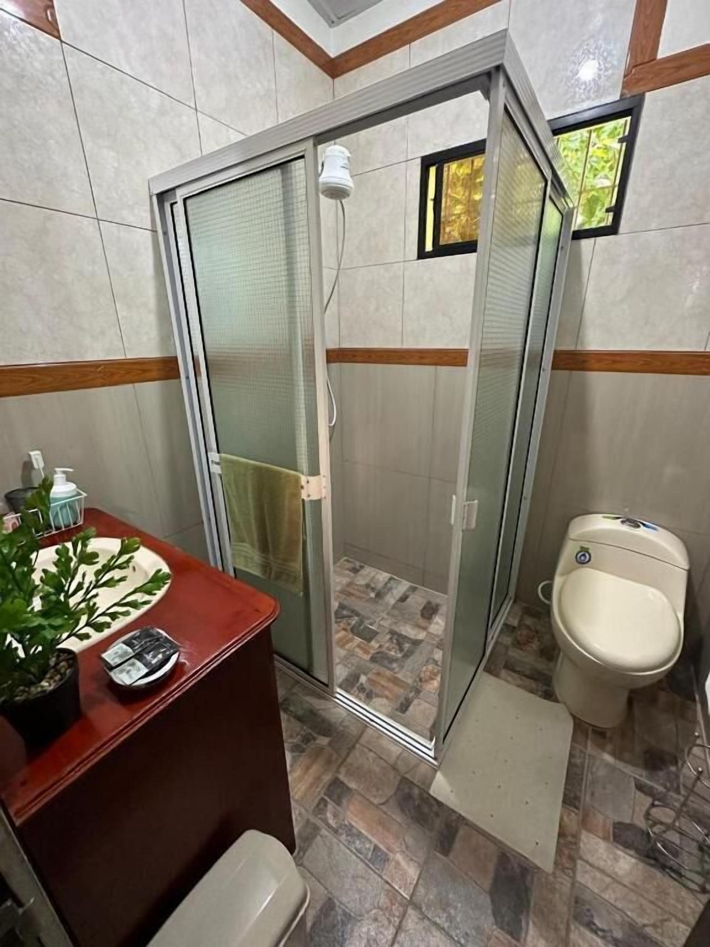 A bathroom with a glass-enclosed shower, a toilet, and a sink with a mirror.