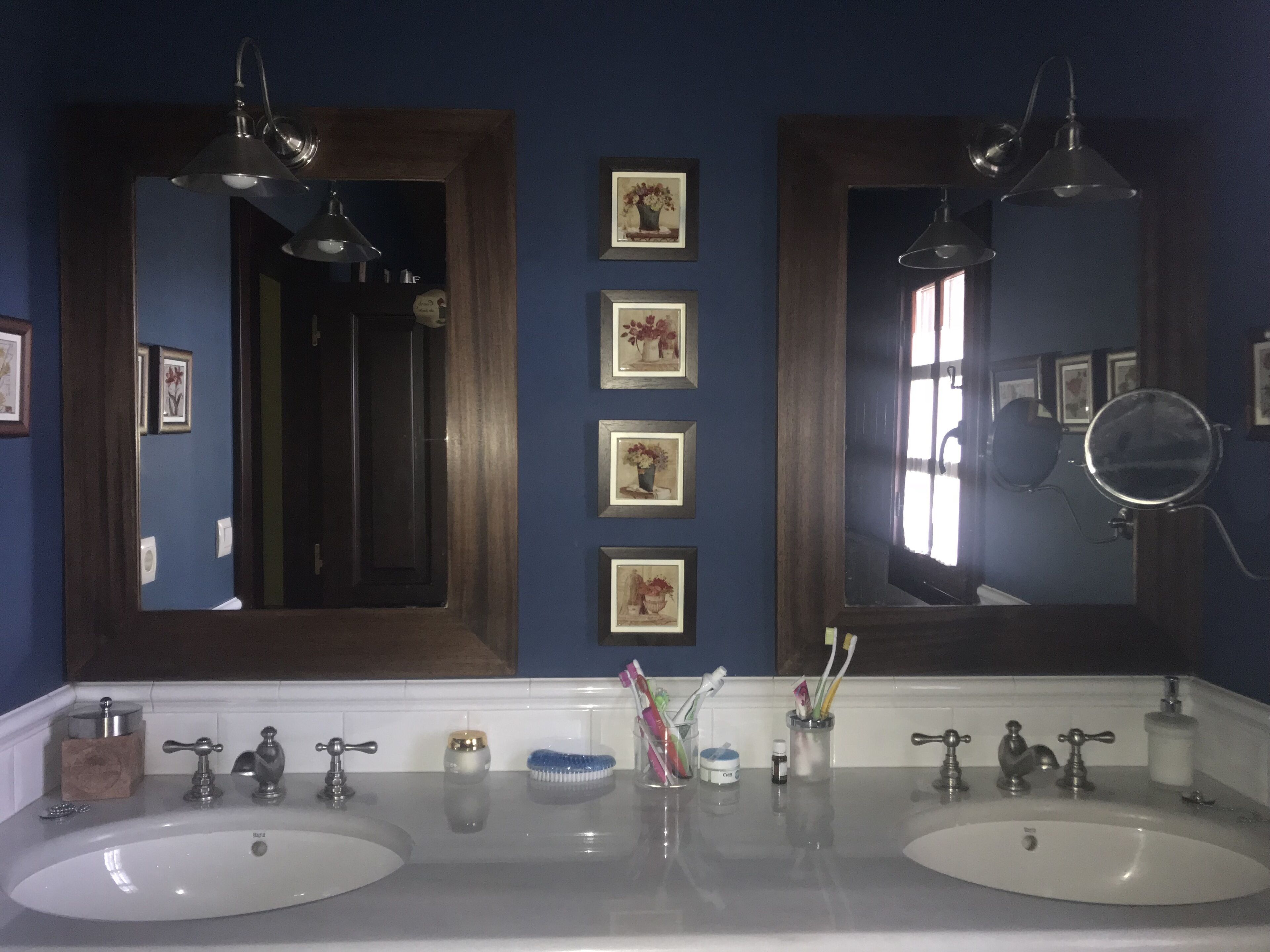A bathroom with two sinks, a large mirror, and framed pictures on the wall.