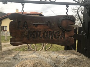 Uma placa de madeira com a inscrição "LA MILONGA" fixada em uma estrutura de metal.