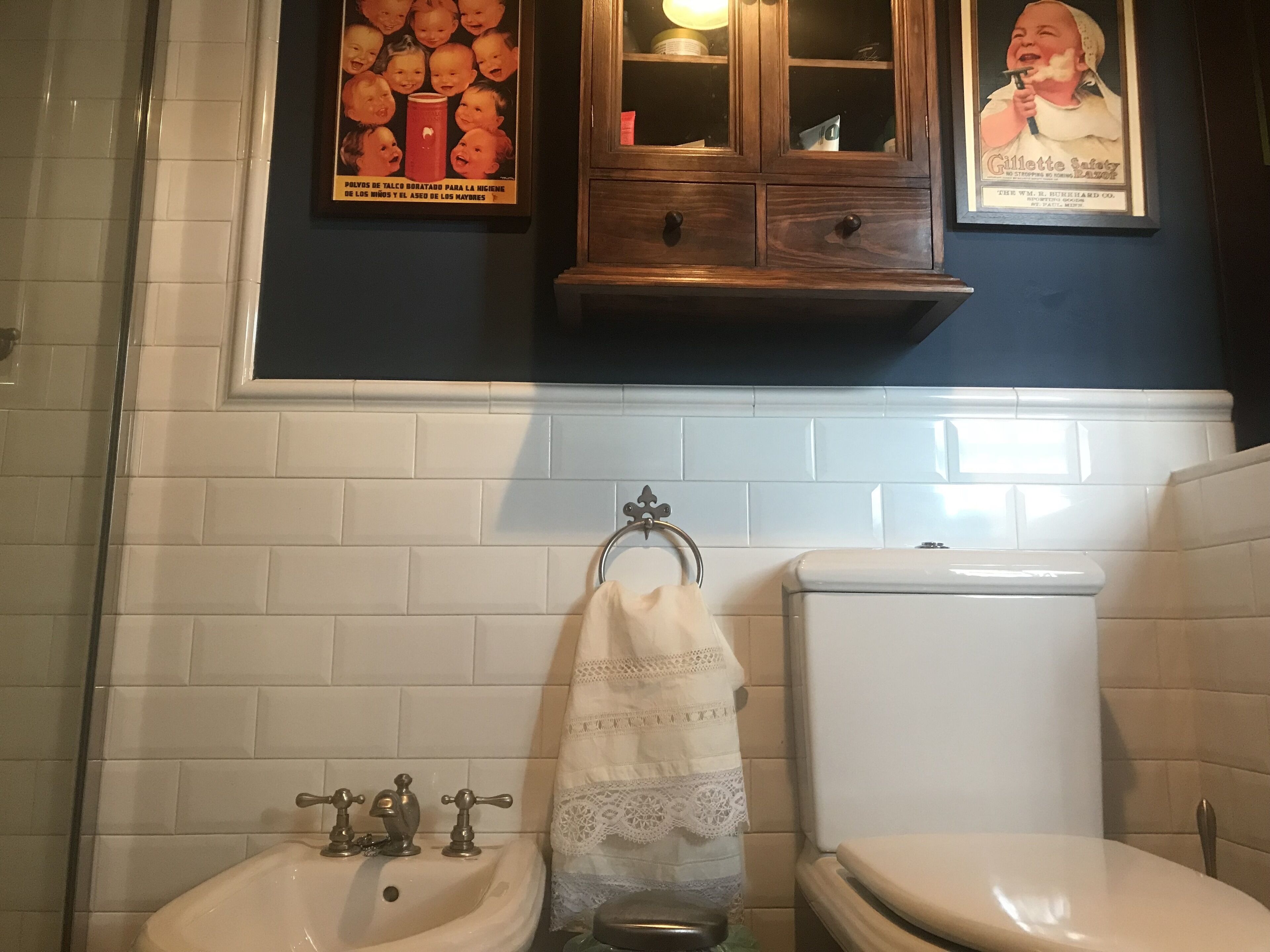 Un baño con un lavamanos blanco, un inodoro y un armario de madera sobre el lavamanos.
