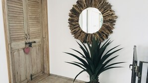 Una puerta de madera con un adorno en forma de corazón, un espejo rústico y una planta en maceta.