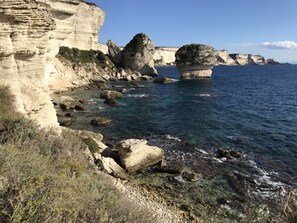 A coastal landscape with rocky cliffs and clear blue water.