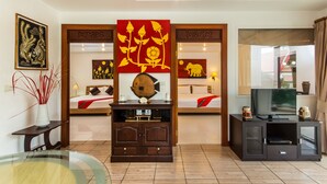 A hotel room with a bed, a TV, a wooden cabinet, and artwork on the walls. - Magical, 2 Bedroom Apartment in Beachside Complex (Koh Samui)