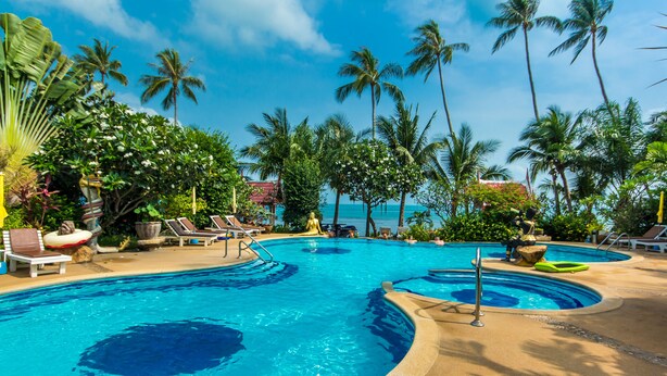 A resort pool area with multiple swimming pools, lounge chairs, and palm trees. - Magical, 2 Bedroom Apartment in Beachside Complex (Koh Samui)