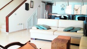 A modern living room with a white sofa, wooden coffee table, and a wooden rocking chair. A staircase with a wooden railing is visible in the background. - BALCONY TO THE SEA, HOLIDAY APARTMENT - PORÍS 8 (Porís de Abona)