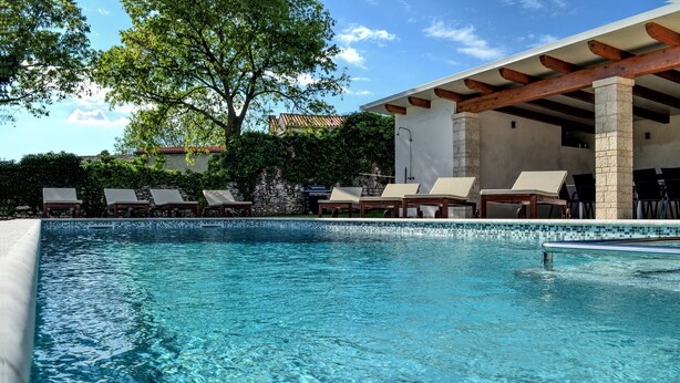 Une piscine aux eaux cristallines, dotée de chaises longues et d’une structure en forme de pergola.
