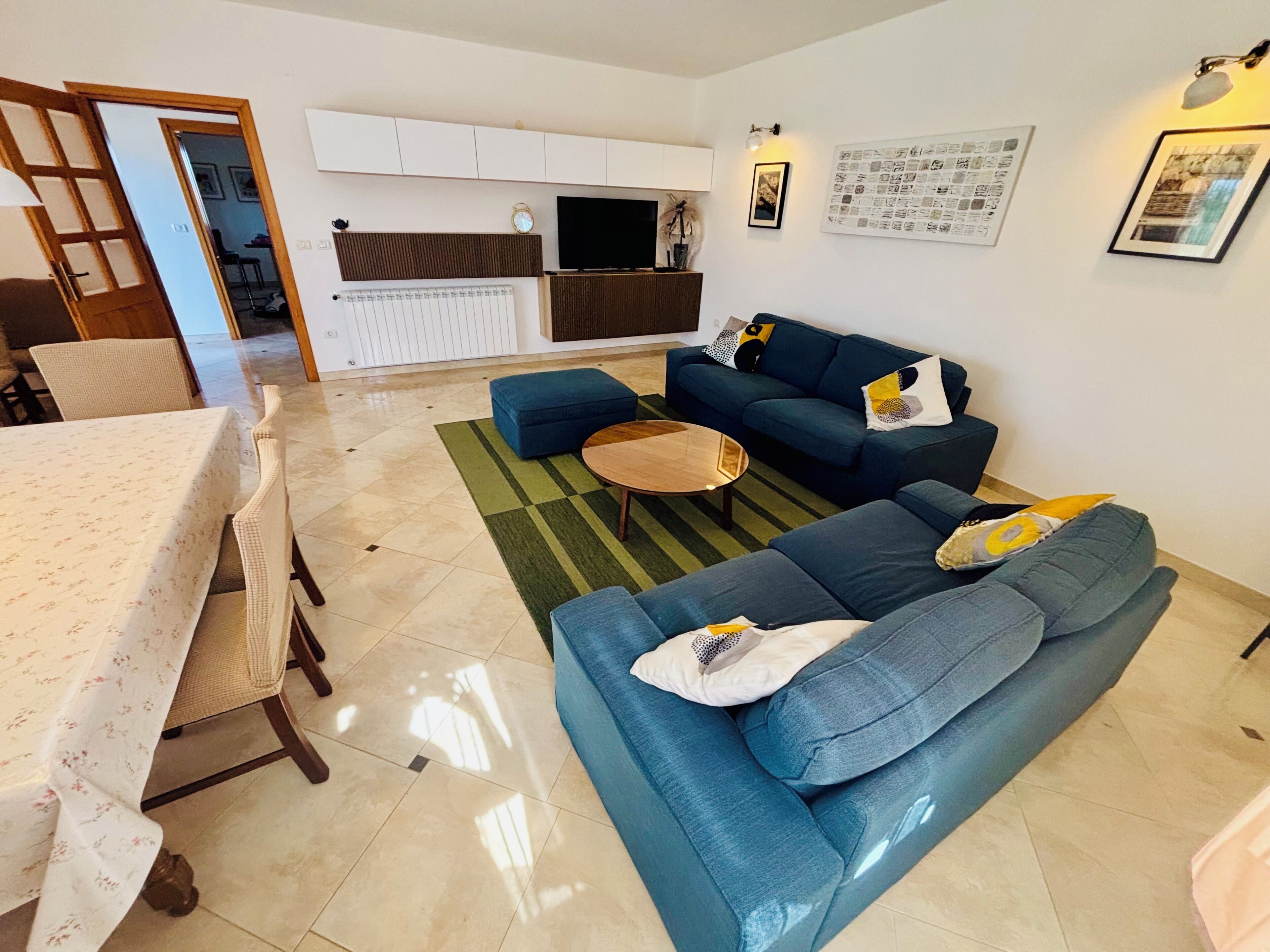 A living room with a sofa, a coffee table, and a dining area with a table and chairs.
