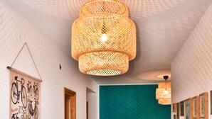 Un couloir avec un banc en bois, une décoration murale sur le thème du vélo, un mur d’accent de couleur turquoise et un luminaire suspendu en fibres tressées.
