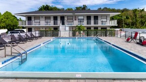 A rectangular swimming pool with a tiled edge, surrounded by a white fence. - Sunshine Inn (Kissimmee)