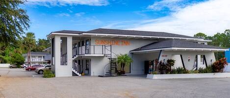 A two-story motel named Sunshine Inn with a parking lot in front.
