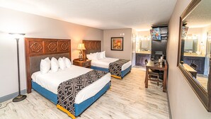 A hotel room with two beds, a desk, a chair, a lamp, and a large mirror. - Sunshine Inn (Kissimmee)