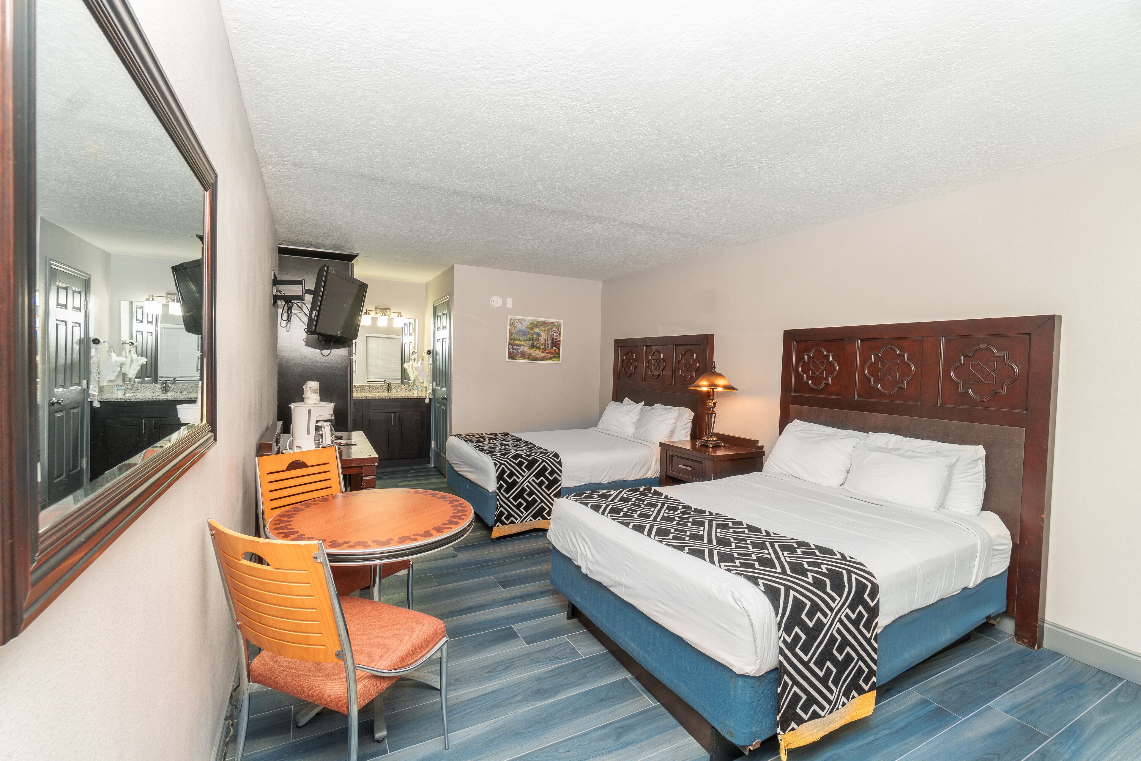 A hotel room with two beds, a dining table, and a chair.