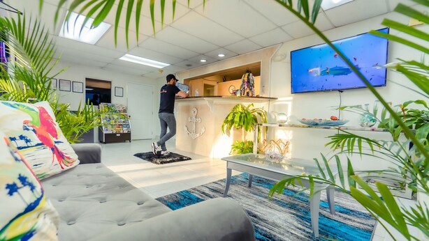 A modern living room with a sofa, coffee table, and a TV mounted on the wall. - Sunshine Inn (Kissimmee)