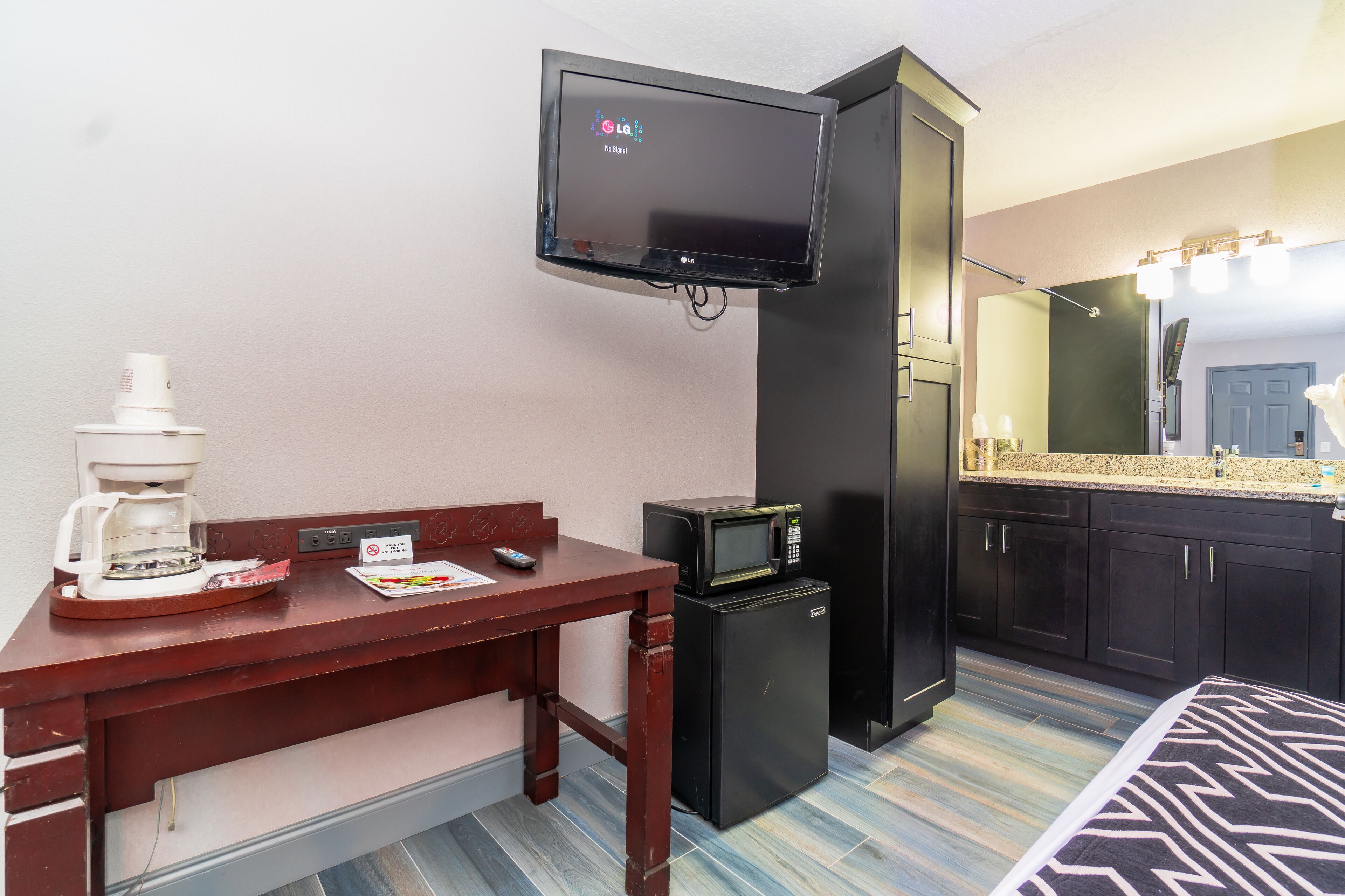 A compact kitchenette with a microwave, coffee maker, and a flat-screen TV mounted above the counter.