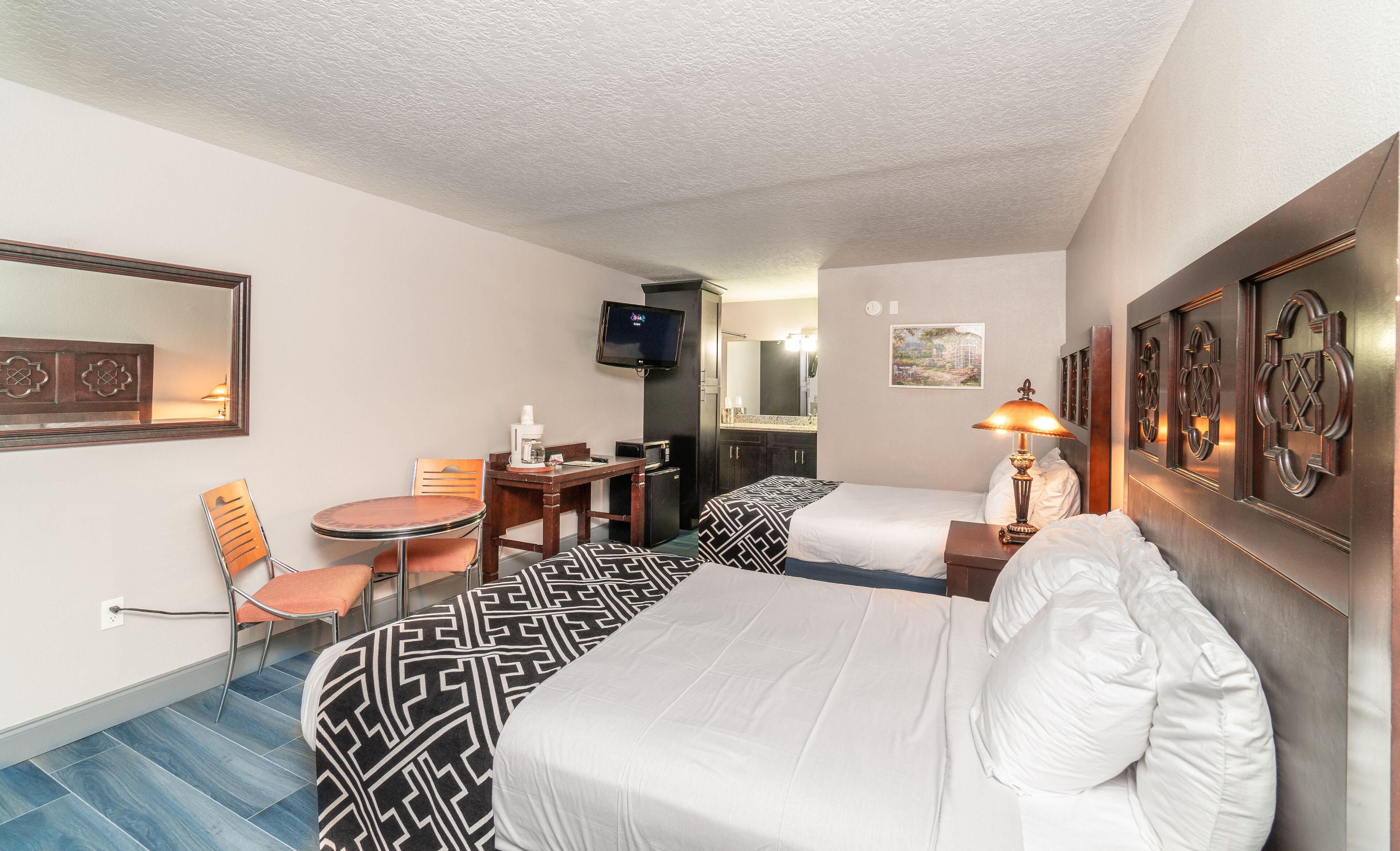 Ein Hotelzimmer mit Bett, Schreibtisch, Stuhl, Fernseher und Spiegel.
