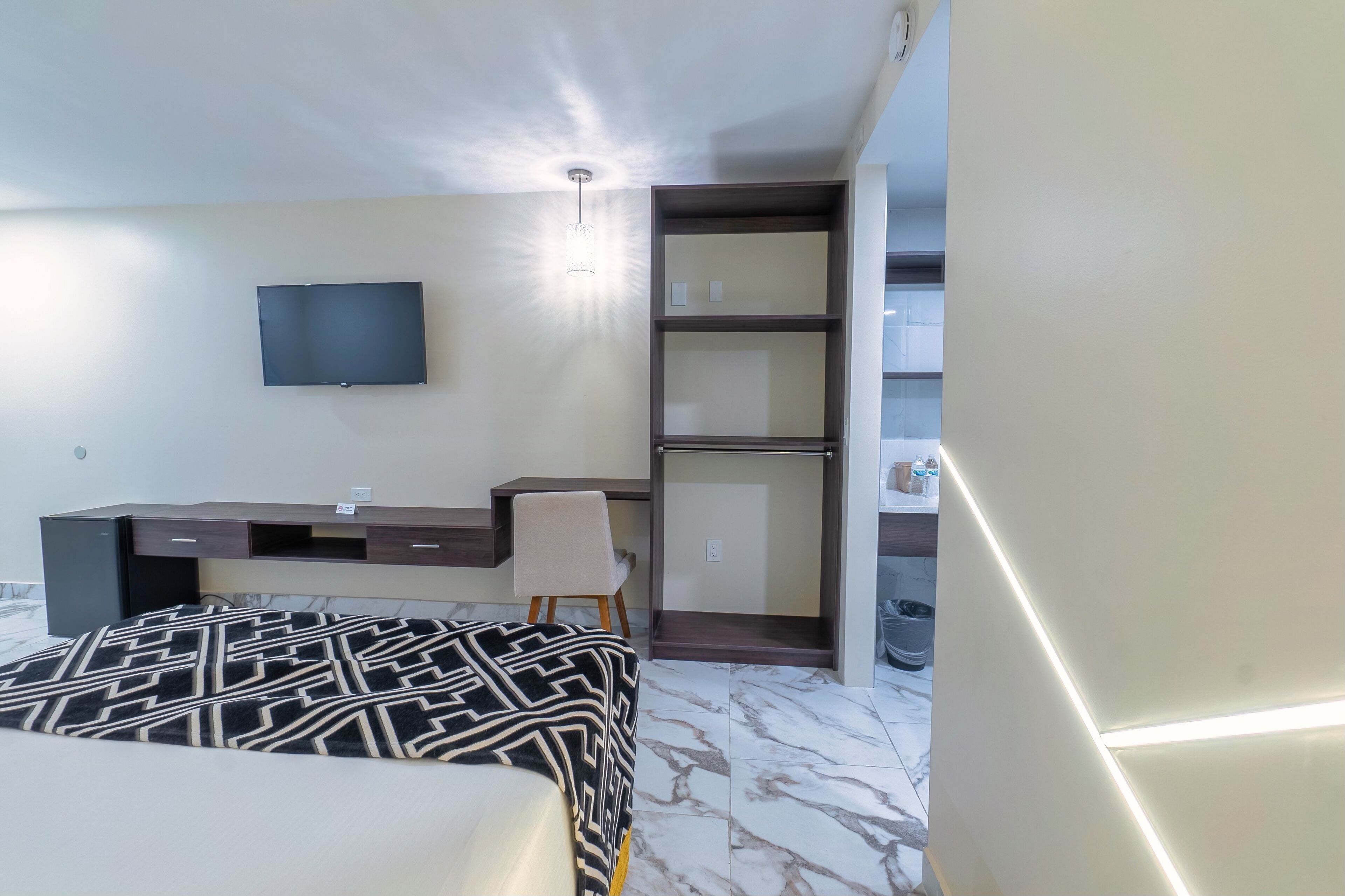 Ein Hotelzimmer mit Bett, Schreibtisch, Stuhl, Fernseher und Kleiderschrank.