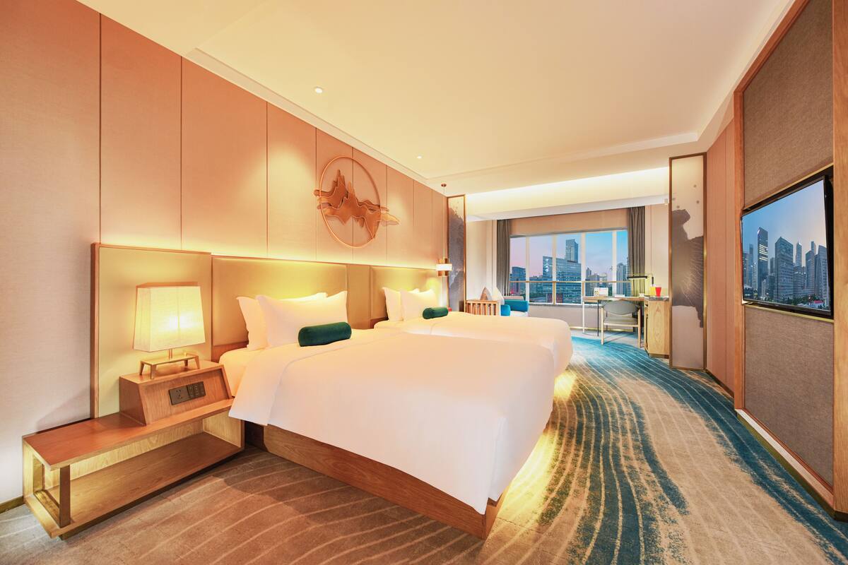 A hotel room with a large bed, a desk, and a city view.
