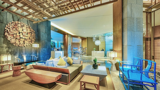 A modern hotel lobby with a seating area, a reception desk, and a large wall art piece. - Royce Hotel Shenzhen (Shenzhen)