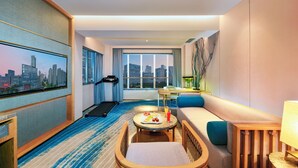 A modern hotel room with a city view, a treadmill, a dining area, and a sofa. - Royce Hotel Shenzhen (Shenzhen)