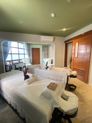 A hotel room with two beds, a bathroom, a window with curtains, and an air conditioning unit. - Alta D' Tagaytay Hotel (Tagaytay)