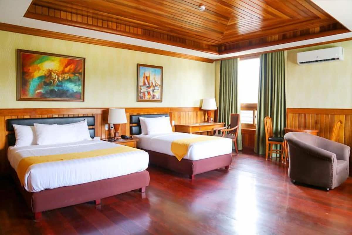 A hotel room with two beds, a desk, a chair, and a sofa.