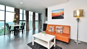A modern living room with a sofa, a dining table with chairs, and a large window offering a city view. - 5 Pax Empire Soho by SYNC (Petaling Jaya)