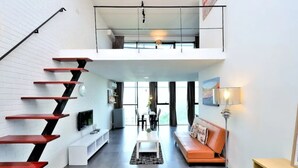 A modern interior with a staircase, a living area with a sofa and a coffee table, and a dining area with chairs and a table. - 5 Pax Empire Soho by SYNC (Petaling Jaya)