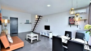 A modern living room with a sofa, dining table, and TV. - 5 Pax Empire Soho by SYNC (Petaling Jaya)