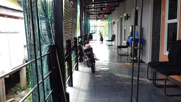 A covered outdoor area with a swing, a motorcycle, and a row of chairs.