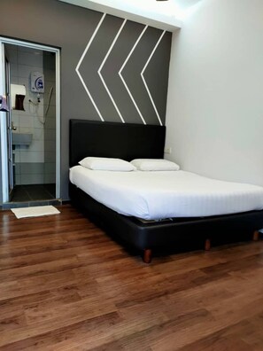 Ein modernes Schlafzimmer mit einem schwarzen Kopfteil, einer weißen Bettdecke und einem Holzboden.