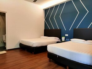Ein Hotelzimmer mit zwei Einzelbetten, Holzboden, blauer Wand mit geometrischem Muster und einer weißen Tür.