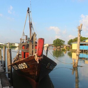 Ein Boot liegt an einem Steg, im Hintergrund sind ein Kran und ein Wasserweg zu sehen.