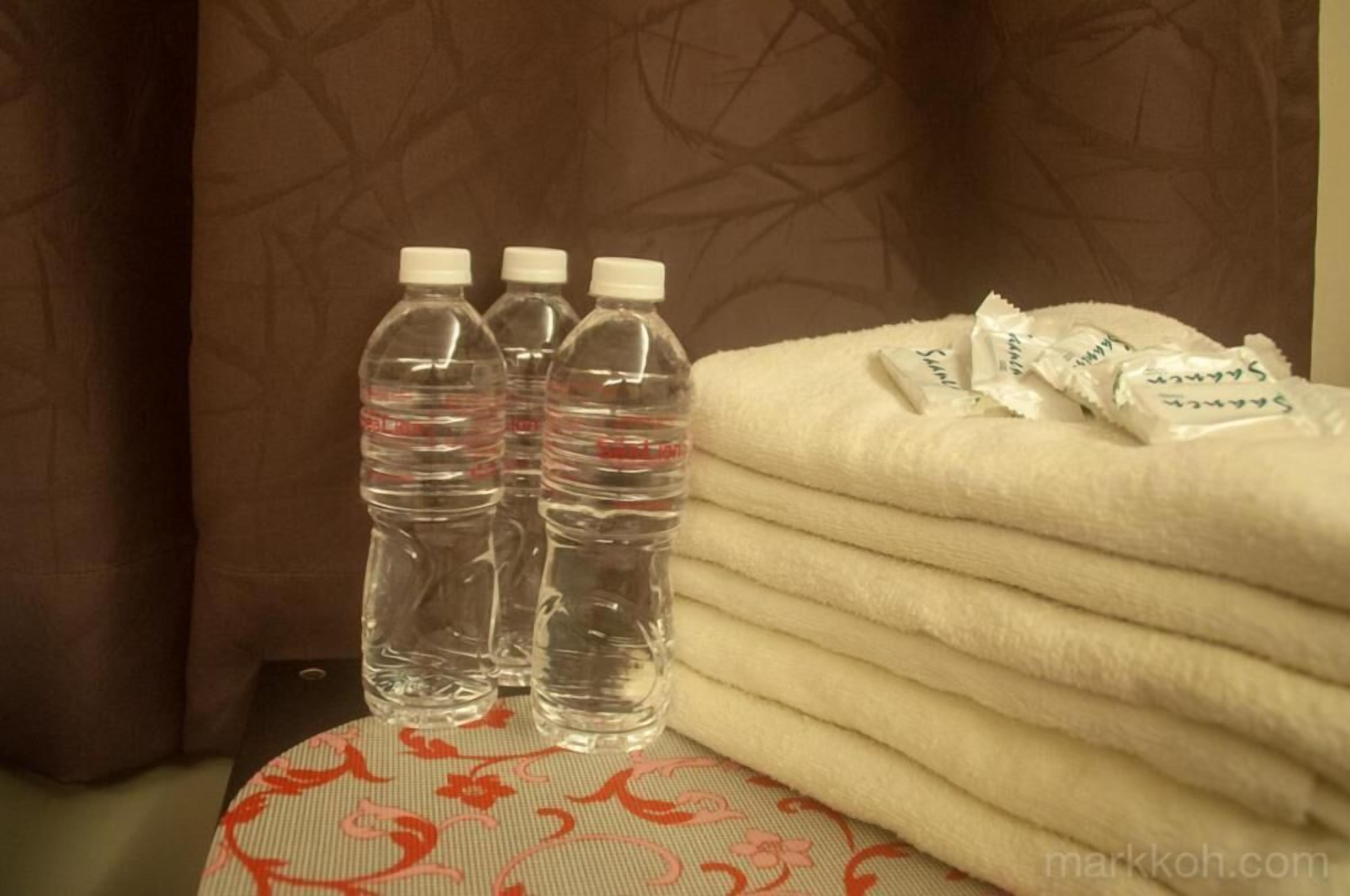Una pila de toallas y tres botellas de agua sobre un mantel estampado.