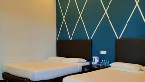Quarto de hotel com duas camas, piso de madeira, ventoinha no teto e parede com padrão geométrico.